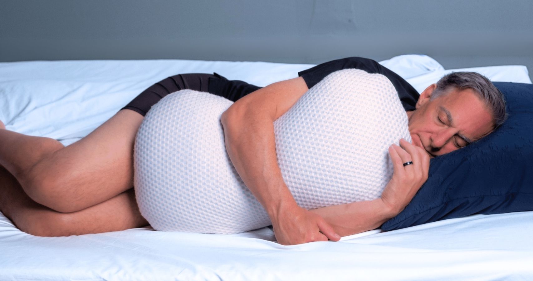 A man sound a sleep while hugging the clutcher therapeutic pillow for a better spinal alignment and improved sleep 